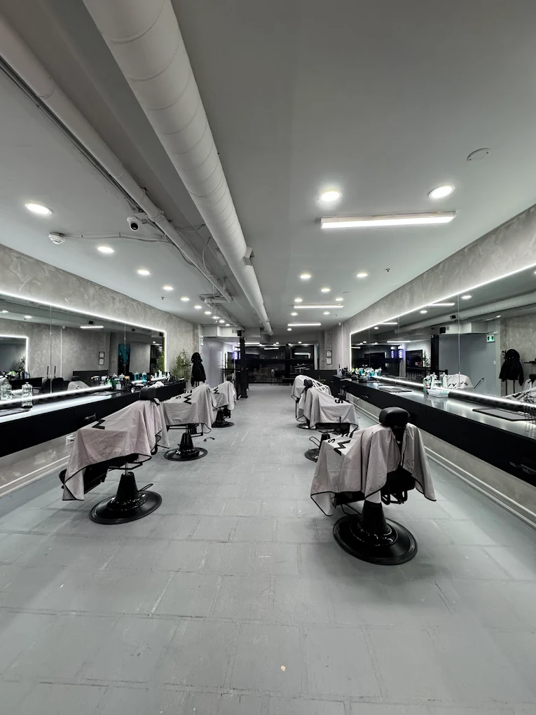 Long view down the shop floor with rows of branded chairs and backlit mirrors