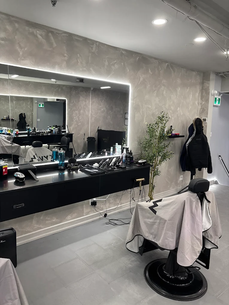 Single station with backlit mirror, tools laid out, and branded cape